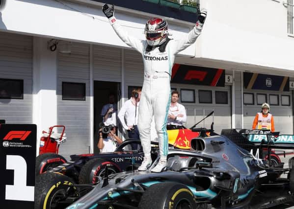 Lewis Hamilton leaps on to the bonnet of his car in celebration following his victory in Hungary. Picture: AP.