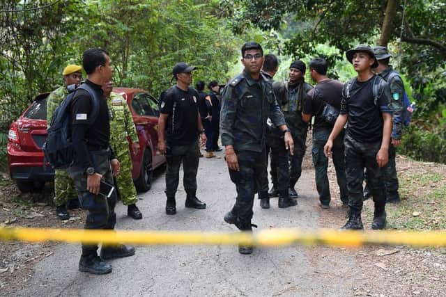 Members of a rescue team are seen behind a police line at the Dusun Resort, where the missing 15-year-old Franco-Irish teenager Nora Quoirin was last seen, in Seremban on August 13, 2019. (Photo by Mohd RASFAN / AFP)