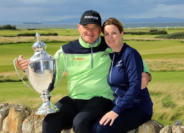Paul Lawrie shows off the Scottish Senior Open trophy as he celebrates a two-shot win in the event at Craigielaw with his wife, Marian. Picture: Phil Inglis/Getty Images
