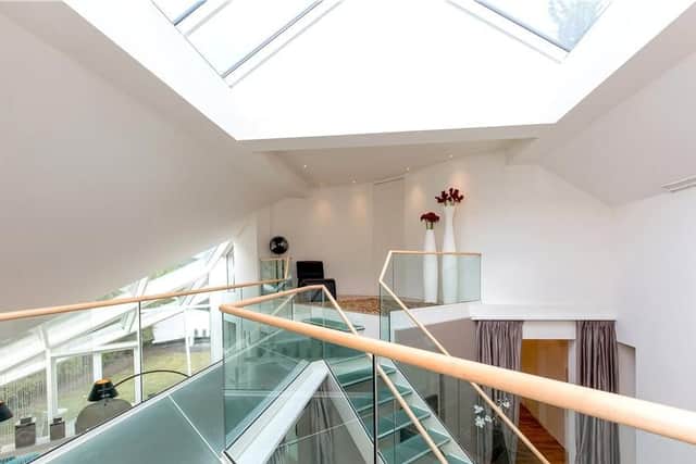 Intricate glazing on all sides of the home gives views to the garden and the main room makes full use of its double height with a glazed stair leading up to a bridged landing upstairs.