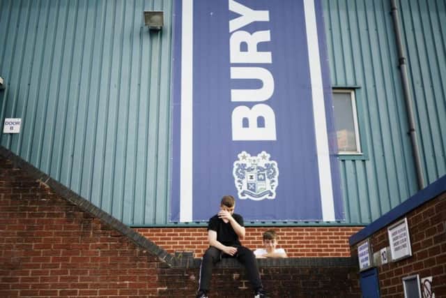 Fans wait for news outside Bury's Gigg Lane stadium