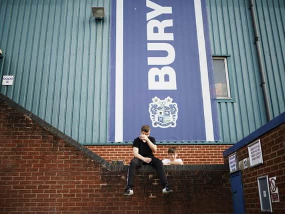 Fans wait for news outside Bury's Gigg Lane stadium