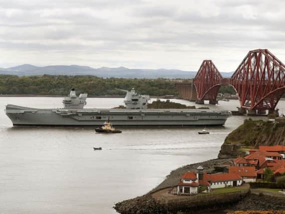 The aircraft carrier HMS Queen Elizabeth passes the Forth Rail Bridge as it leaves the Firth of Forth following maintenance at the Rosyth Dockyards, where some of the 2,500 shipbuilding jobs secured by the government will go. Picture: PA