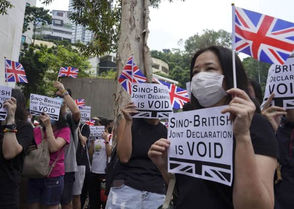 Protesters hold placards and British flags during a peaceful demonstration outside the British Consulate in Hong Kong. Picture: AP Photo/Vincent Yu