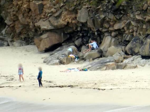 'Irresponsible family' pictured sunbathing underneath dangerously unstable cliff.