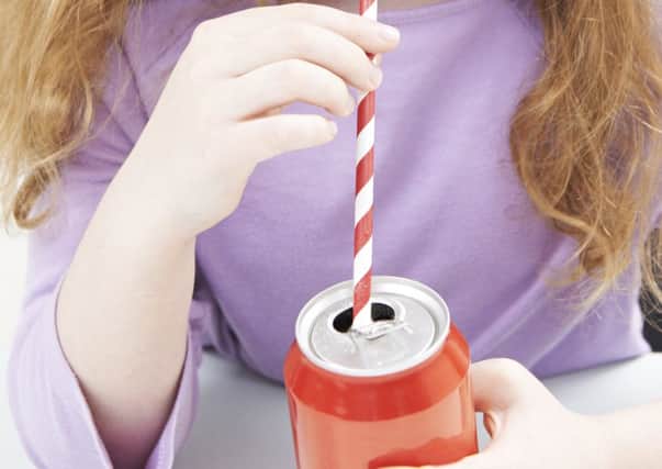 A young girl consumes a fizzy drink through a straw