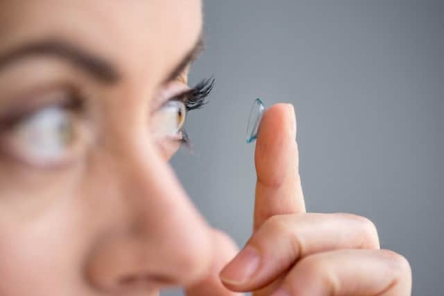 A woman puts a disposable contact lense into one of her eyes