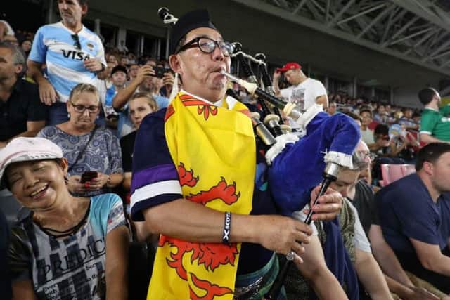 A Scotland fan plays the bagpipes at the Kobe Misaki Stadium to urge Scotland on