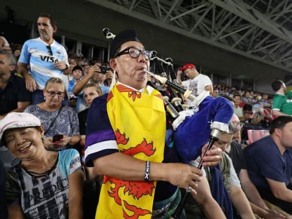 A Scotland fan plays the bagpipes at the Kobe Misaki Stadium to urge Scotland on