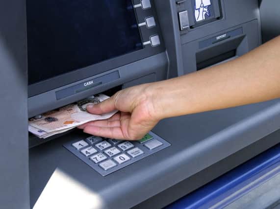 A person takes out cash from an ATM