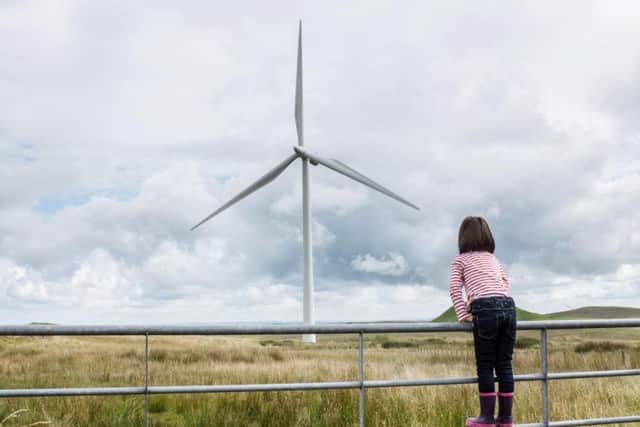 A child overlooks Whiteless Wind Farm near Glasgow
