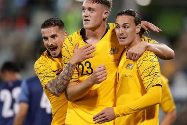 Harry Souttar is joined by Jamie Maclaren, left, and Jackson Irvine after scoring on his Australia debut.