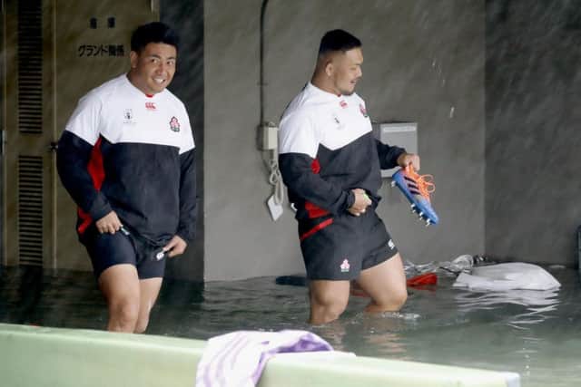 Japan players Takuya Kitade, left, and Yusuke Kizu wade through a flooded walkway at a stadium in Tokyo as the team try to train for the Scotland match. Picture: Yuki Sato/Kyodo News via AP