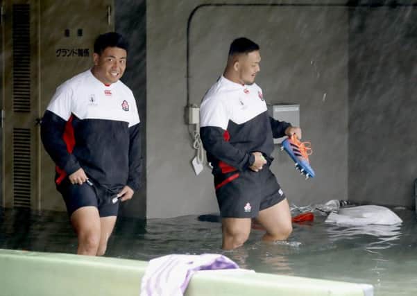 Japan players Takuya Kitade, left, and Yusuke Kizu wade through a flooded walkway at a stadium in Tokyo as the team try to train for the Scotland match. Picture: Yuki Sato/Kyodo News via AP