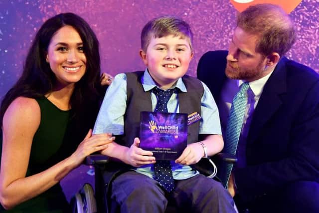 Prince Harry, Duke of Sussex and Meghan, Duchess of Sussex pose for a photograph with award winner William Magee during the WellChild Awards Ceremony. (Photo by Toby Melville/Getty Images)