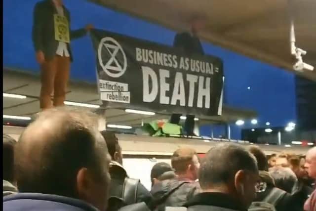 Extinction Rebellion protesters on the roof of an Underground train surrounded by angry commuters at Canning Town station. Picture: PA