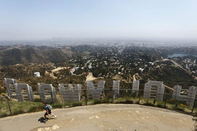 LOS ANGELES, CALIFORNIA - JULY 05: A visitor walks above the famed Hollywood sign in Griffith Park on July 5, 2019 in Los Angeles, California. Air quality was predicted to reach the 'unhealthy' range in the Los Angeles metropolitan area today by the South Coast Air Quality Management District following last night's fireworks. July 4th and July 5th are normally some of the worst days of the year for air quality as fireworks launch fine-particle pollution into the air. (Photo by Mario Tama/Getty Images)