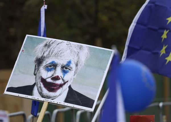 Anti-Brexit supporters hold a placard showing current Prime Minister Boris Johnson portrayed as the Joker as they take part in a "People's Vote" protest march calling for another referendum on Britain's EU membership in London (Picture: Matt Dunham/AP)