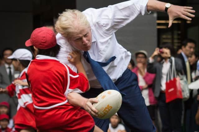 Red card? Born front-row forward Boris Johnson shows his skills as he accidentally takes out a small child in Japan (Picture: Stefan Rousseau/PA Wire)