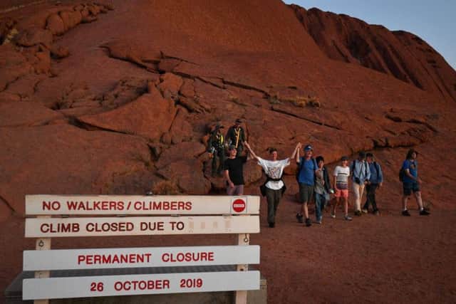 Tourists climb the Uluru, also known as Ayers Rock, ahead of a long-sought climbing ban. Picture: Saeed Khan/AFP