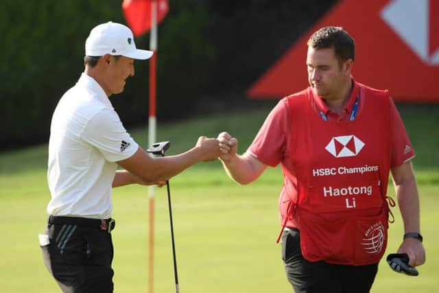 First-round leader Haotong Li of China fist bumps with his caddie on the 8th green at Sheshan International. Picture: Ross Kinnaird/Getty Images