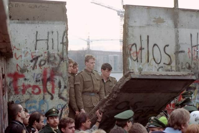 East German border guards are seen through a gap in the wall. Picture: Lionel Cironneau/AP