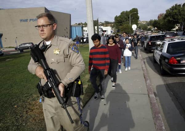A California Highway Patrol officer escorts pupils out of Saugus High School after a shooting on the campus in Santa Clarita, California (Picture: Marcio Jose Sanchez/AP)