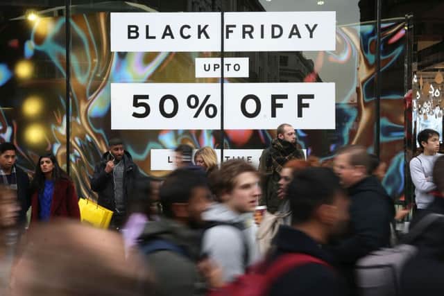 Shoppers pass a promotional sign for 'Black Friday' sales discounts on Oxford Street in London, on November 24, 2017. Black Friday is a sales offer originating from the US where retailers slash prices on the day after the Thanksgiving holiday. In the UK it is used as a marketing device to entice Christmas shoppers with the discounts at stores often lasting for a week. / AFP PHOTO / Daniel LEAL-OLIVAS        (Photo credit should read DANIEL LEAL-OLIVAS/AFP via Getty Images)