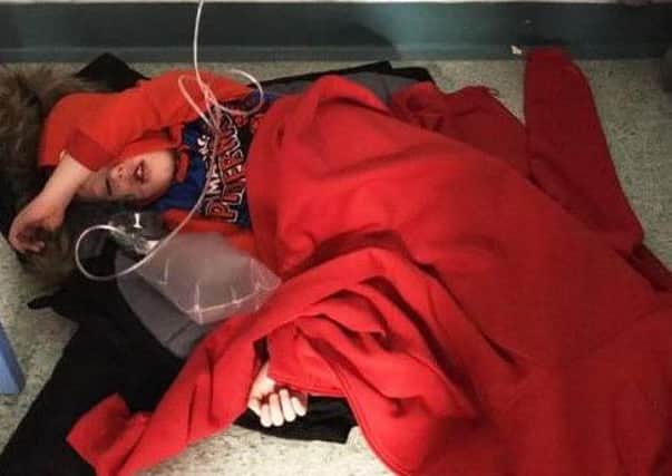 A social media post falsely claiming this photograph of a sick four-year-old boy sleeping on a hospital floor because of a lack of beds was staged went viral after it became the political issue of the day.