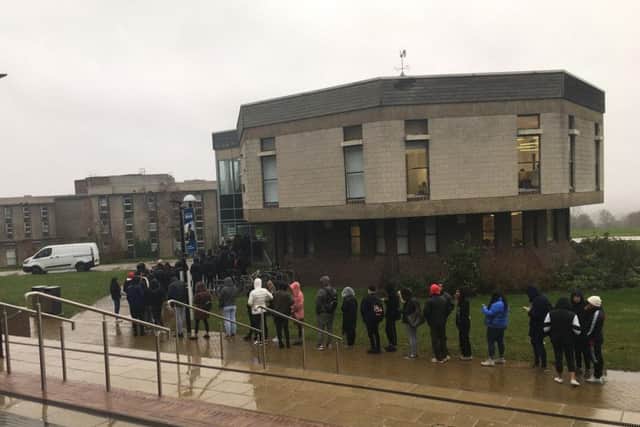 People queue outside the University of Kent in the rain to cast their ballots