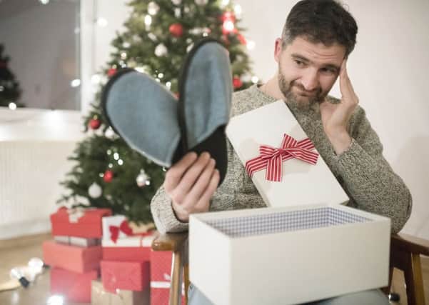Man opening a Christmas present with disappointment.