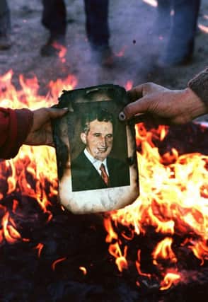 A portrait of Nicolae Ceausescu is burnt in Denta, Romania, as the people rejoice at the dictator's downfall in December 1989. Picture: Joel Robine/Getty