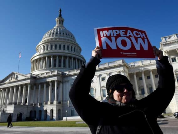 A woman holds a placard as people rally in support of the impeachment of US President Donald Trump in front of the US Capitol, as the House readies for a historic vote.