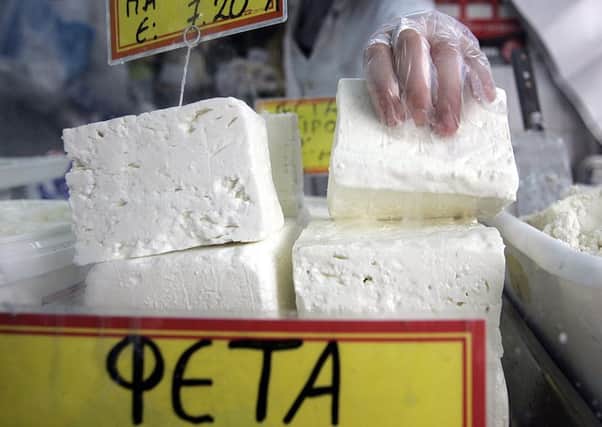 A shop assistant lifts a slub of feta cheese in Athens (Picture: Aris Messinis/AFP/Getty Images)