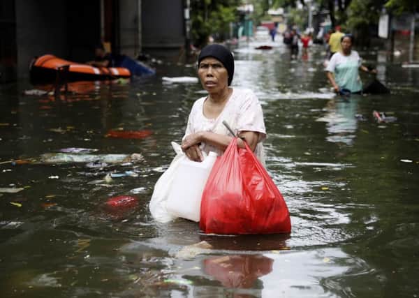 A woman wades through floodwater in Jakarta, Indonesia, where dozens of people have died. (Picture: Dita Alangkara/AP)