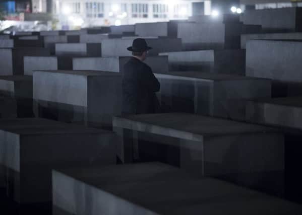 A Rabbi stands in front of a cement stele of the Holocaust Memorial to the Murdered Jews of Europe during a march from the Brandenburg Gate on November 11, 2013 in Berlin. More than 200 Rabbis from 30 different countries took part in a Silent Memorial to mark the 75th anniversary of the Kristallnacht (Night of Broken Glass). AFP PHOTO / JOHANNES EISELE (Photo credit should read JOHANNES EISELE/AFP via Getty Images)