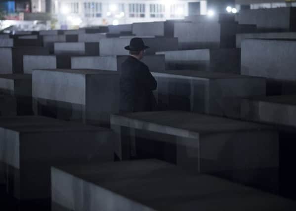 A Rabbi stands in front of  a cement stele of the Holocaust Memorial to the Murdered Jews of Europe during a march from the Brandenburg Gate on November 11, 2013 in Berlin.  More than 200 Rabbis from 30 different countries took part in a Silent Memorial  to mark the 75th anniversary of the Kristallnacht (Night of Broken Glass).    AFP PHOTO / JOHANNES EISELE        (Photo credit should read JOHANNES EISELE/AFP via Getty Images)