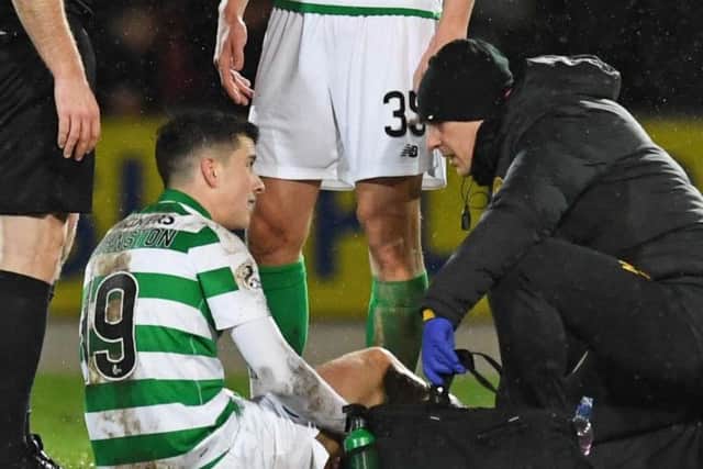 Mikey Johnston receives treatment from Celtic physio Tim Williamson after suffering a knee injury