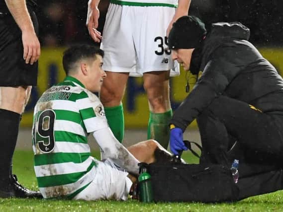 Mikey Johnston receives treatment from Celtic physio Tim Williamson after suffering a knee injury