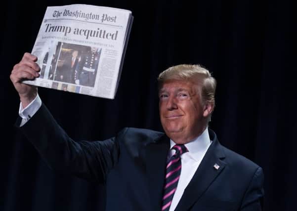 Donald Trump holds up a newspaper announcing his acquittal at the US National Prayer Breakfast (Picture: Evan Vucci/AP)