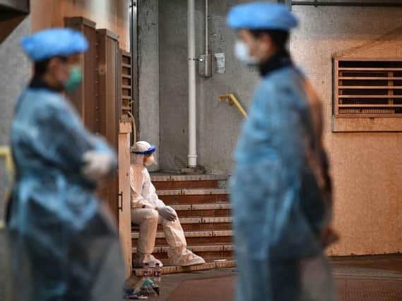 Medical personnel wearing protective suits stay near a block's entrance on the grounds of a residential estate in Hong Kong (Photo: ANTHONY WALLACE/AFP via Getty Images)