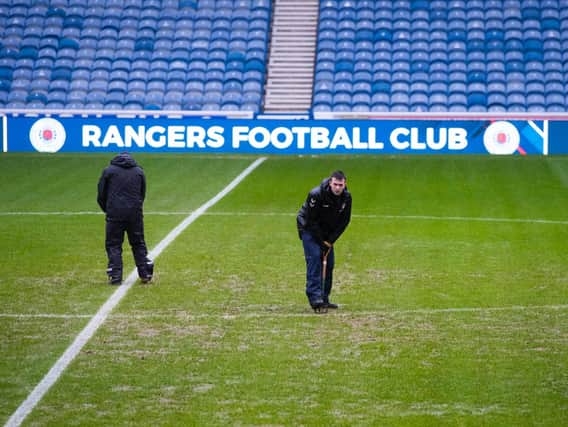 Ground staff work on the Ibrox pitch but their efforts were in vain as the game was one of four called off as a result of the weather