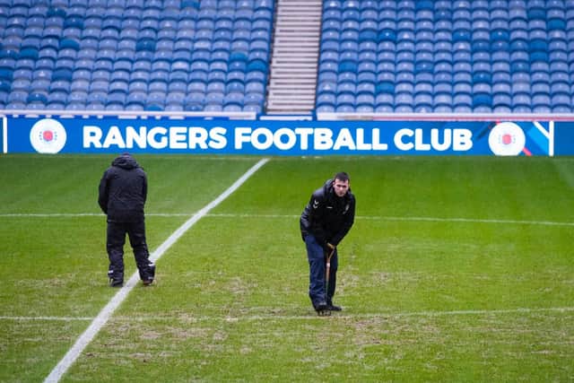 Ground staff work on the Ibrox pitch but their efforts were in vain as the game was one of four called off as a result of the weather