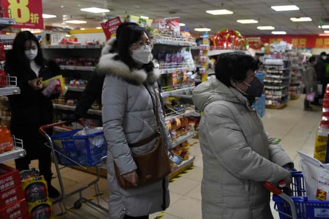 Shoppers wear protective face masks as they line up through a checkout at a supermarket in Beijing on February 16.