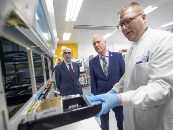 Scotland's Public Health Minister Joe FitzPatrick (centre) and Professor Rory Gunson (left) look on as clinical support technician Douglas Condie (right) extracts viruses from swab samples so that the genetic structure of a virus can be analysed and identified in the coronavirus testing laboratory at Glasgow Royal Infirmary.