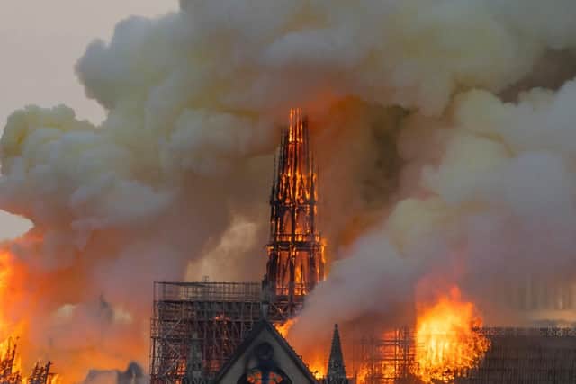 Smoke billows as flames burn through the roof of the Notre-Dame de Paris Cathedral.