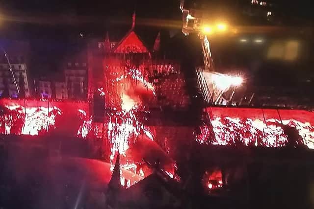 An image taken from a television screen shows an aerial view of the Notre-Dame Cathedral engulfed in flames on April 15.